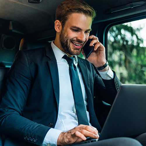 A corporate limo service client sits in the back of a limousine working on business.