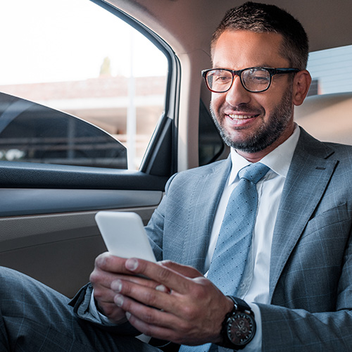 A business man sits in a limousine and smiles during corporate limo service.